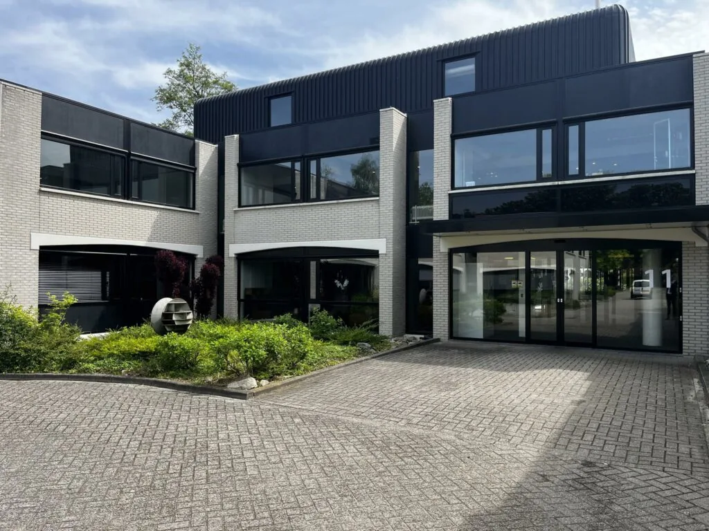 Modern kantoorgebouw aan de Burgemeester Verderlaan 11 met grote ramen en een betegelde oprit.